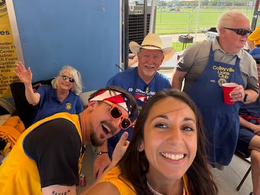 Colleyville Lions and friends in gold vests and Lions shirts smiling for a selfie under an event tent